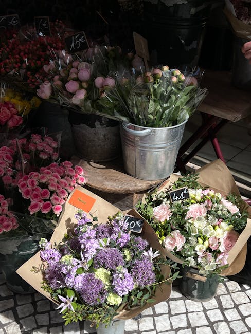 A display of fresh floral arrangements at a flower shop, featuring bouquets with pink roses, purple and white lisianthus, and other mixed blooms. The flowers are wrapped in brown kraft paper or placed