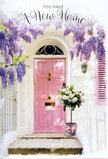 In this quietly enchanting Watford doorway, the story of a new home is told through soft colours and carefully arranged flowers. A pale pink door, almost powdery in appearance, forms the welcoming heart of the scene. Its gentle tone is beautifully offset by crisp white walls and a simple matching shutter, which together reflect and diffuse the light, creating a bright yet soothing entrance. Above, wisteria cascades in relaxed garlands of lavender and lilac, with each drooping cluster made up of tiny, delicate petals. The blooms form an arch-like frame that softens the lines of the architecture and adds a sense of movement, as if a breeze from nearby Cassiobury or Oxhey Park might stir them at any moment. On the step in front of the door stands a grey tin bucket reimagined as an elegant vessel for a lush floral display. It overflows with creamy white roses that are full and rounded, their petals slightly ruffled at the edges. Interwoven among the roses are sprigs of fresh green foliage, creating gentle contrasts of colour and texture that suggest the hand of an experienced local florist. Encircling the base of the bucket is a pink ribbon, matched softly to the door, tied into a relaxed bow whose loose ends trail against the stone. Subtle sunlight illuminates the scene, enhancing the curves of petals and leaves while casting soft, inviting shadows. The overall mood is one of tender welcome and quiet anticipation, perfectly suited to a housewarming floral gift delivered in Watford, waiting patiently on the doorstep to greet its new owners with grace and warmth.